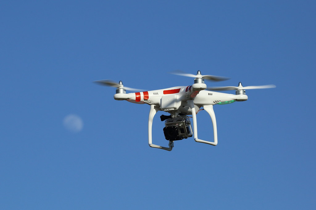 Inspektionsdrohne mit Kamera-Gimbal im Flug vor blauem Himmel